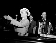830204 Afbeelding van de zanger / conferencier Lou Bandy, met rechts een accordeonist.